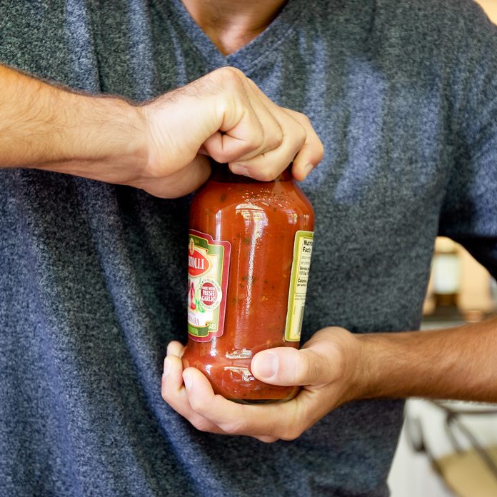 man trying to open a stubborn jar of sauce