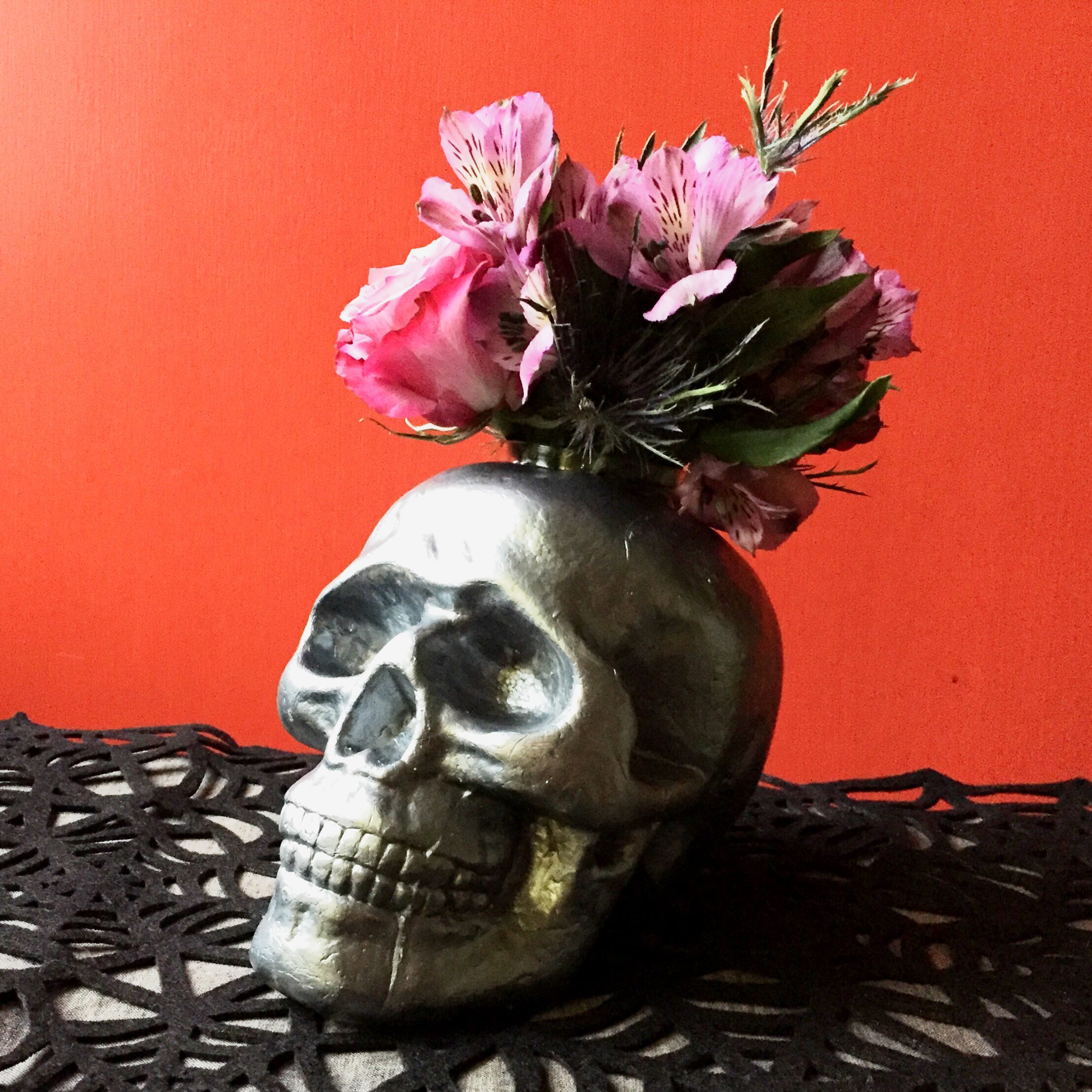 Halloween decoration idea black skull being used as a vase for pink flowers