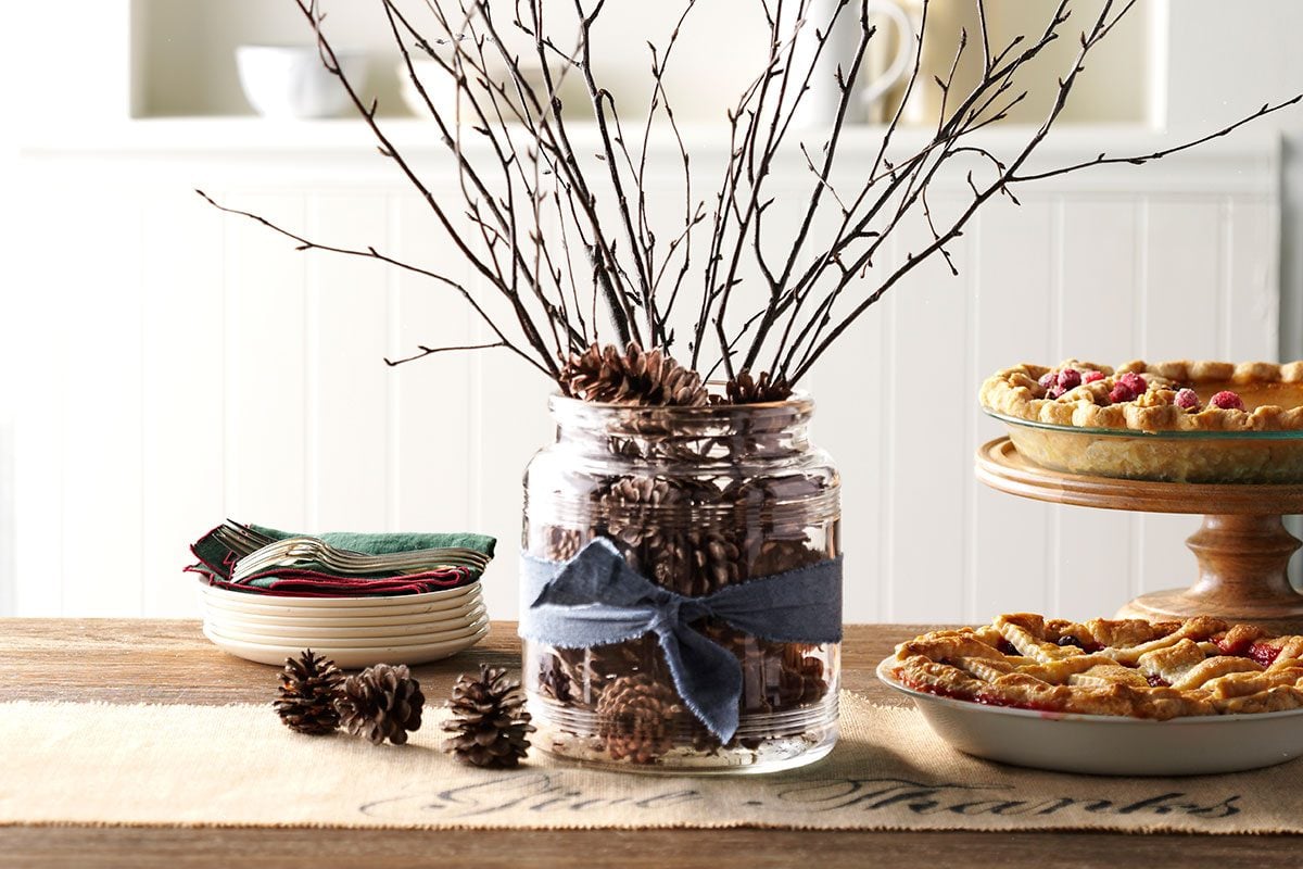 Table with two pies and a branch center piece including a pine cone filled jar