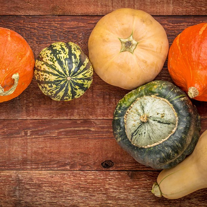 A variety of winter squash fruits on a rustic wooden table