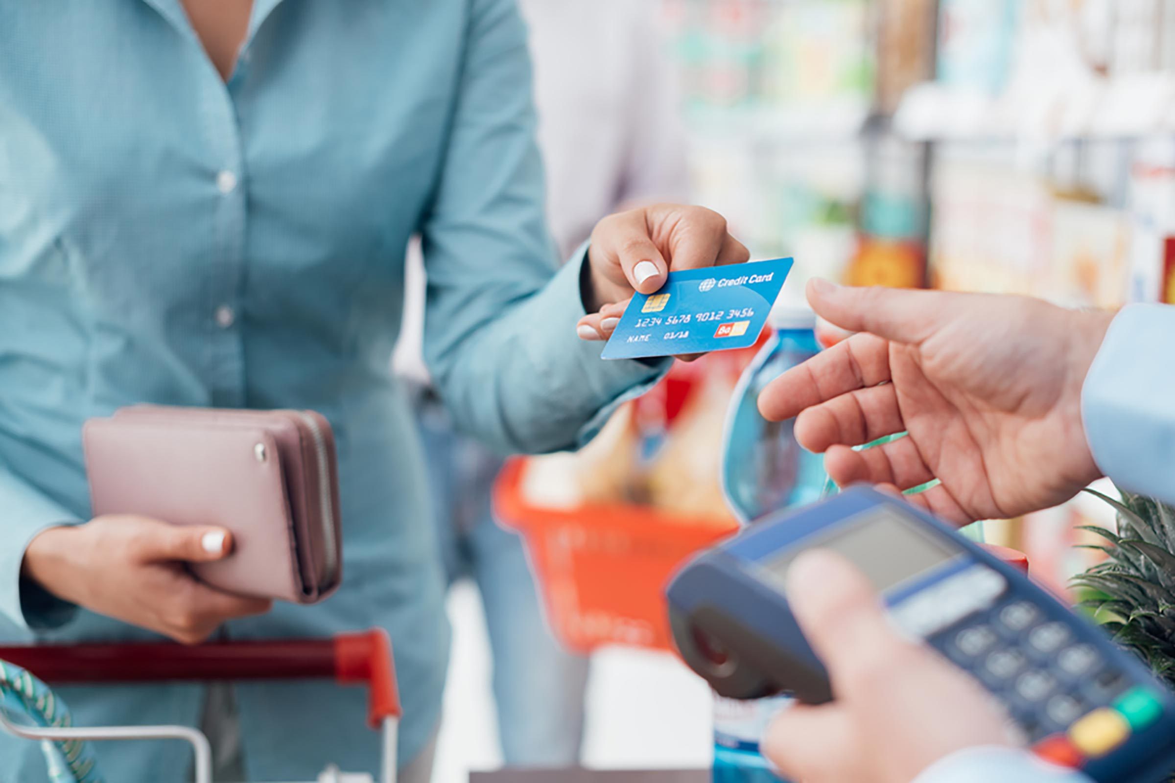 Person handing over a credit card to a cashier at a store