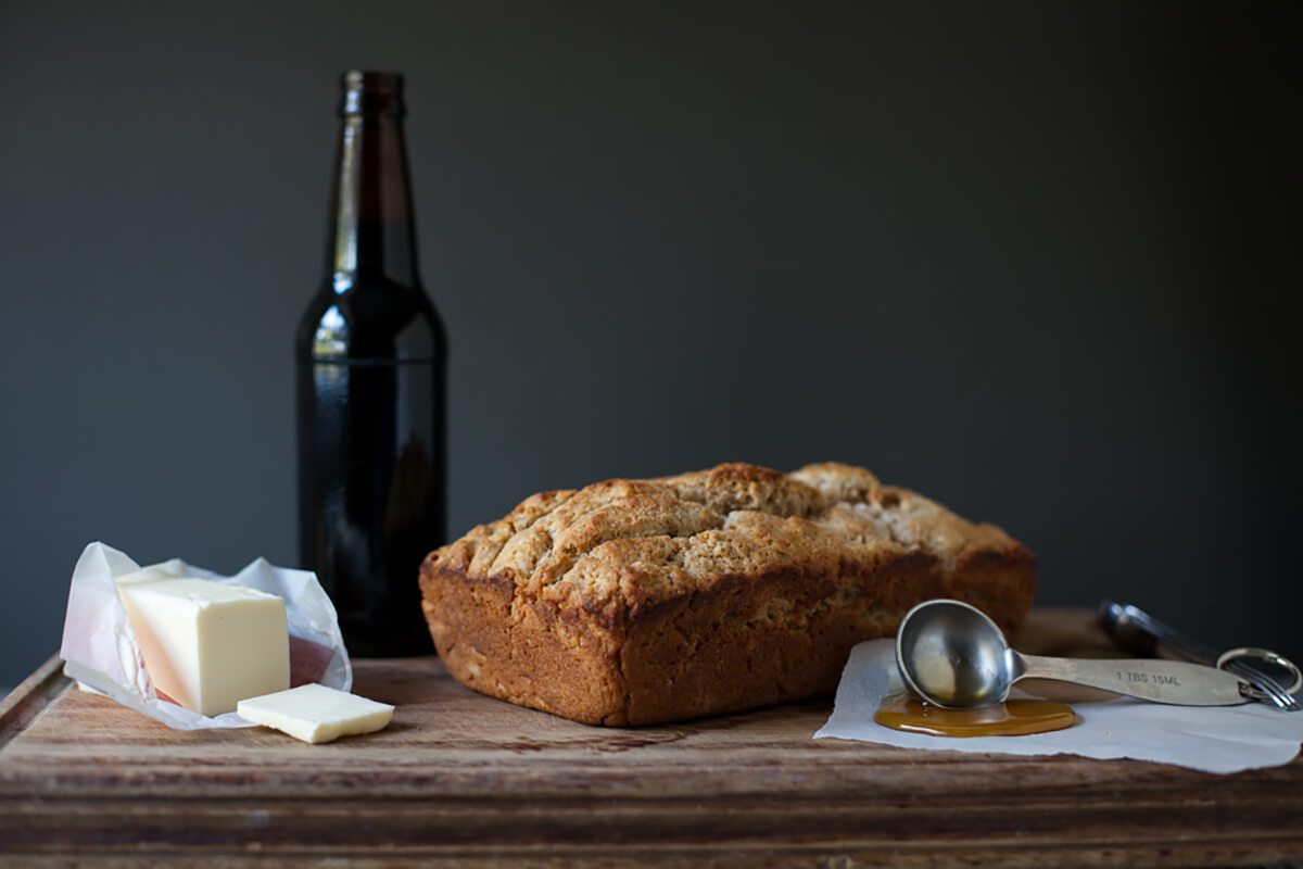 Homemade beer bread with honey and butter on cutting board