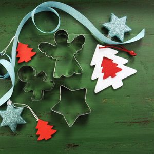 Christmas holiday background with red, white, festive decorations and cookie cutters against a vintage style dark green recycled wood background