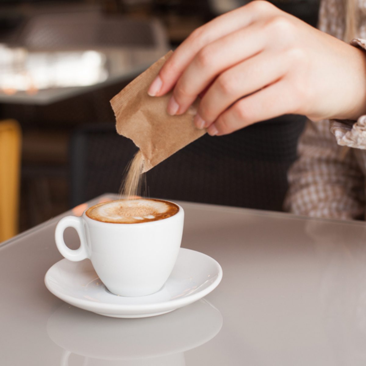 Woman hand adding sugar in coffee; Shutterstock ID 768253051