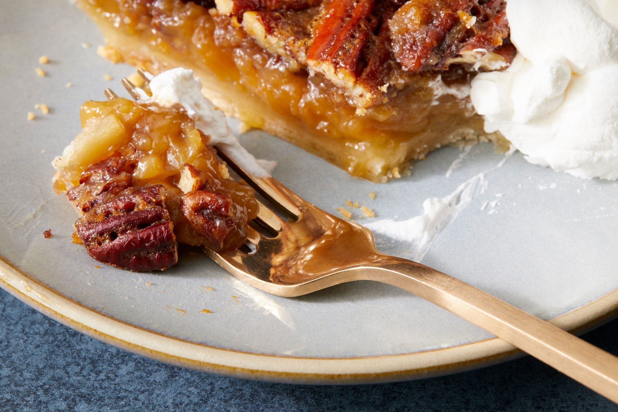 close shot of Bourbon Pecan Pie served in a plate with fork; dark background;