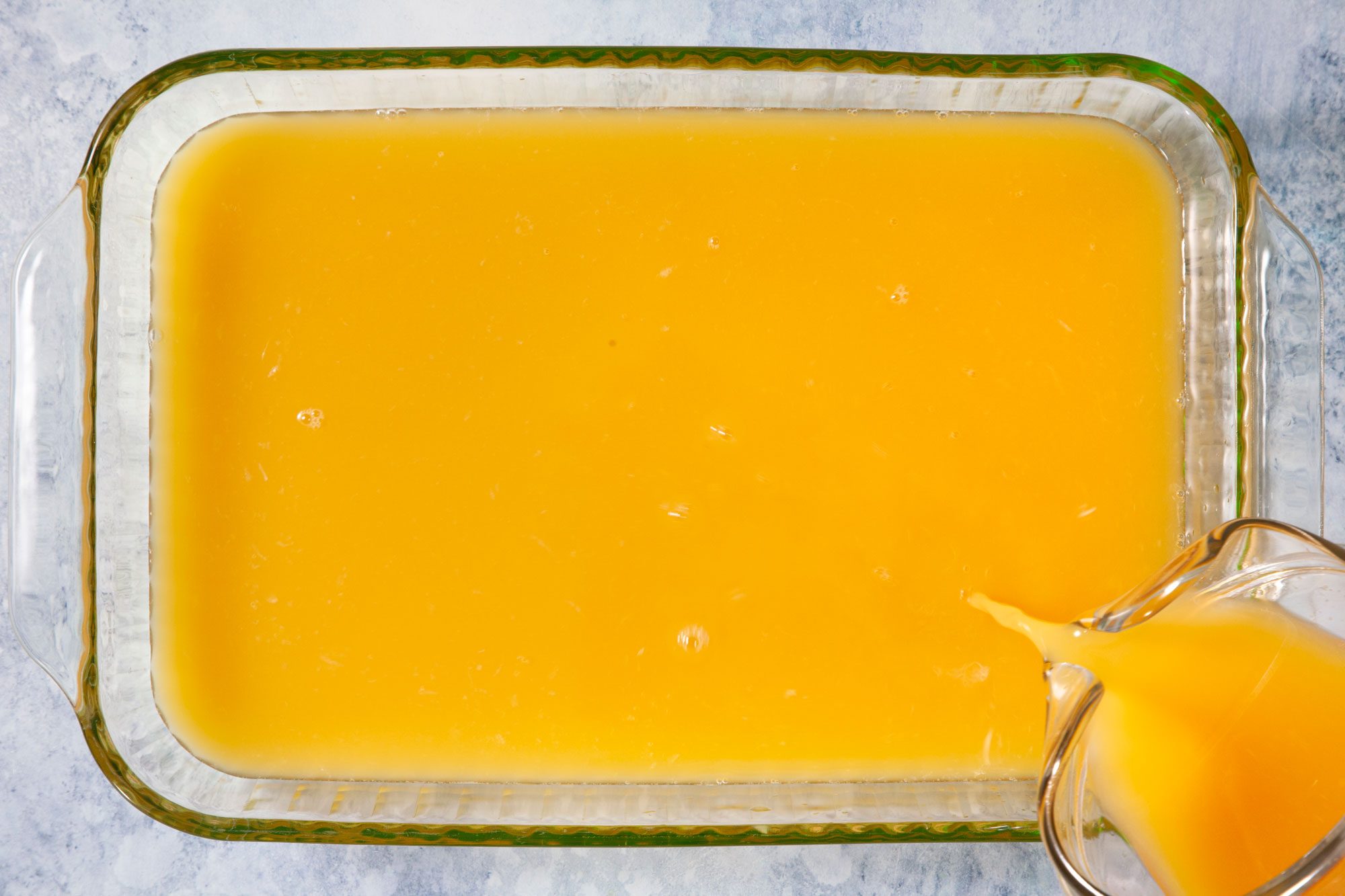 Pouring Orange Juice and Brandy Mix into A Quart Freezer Container