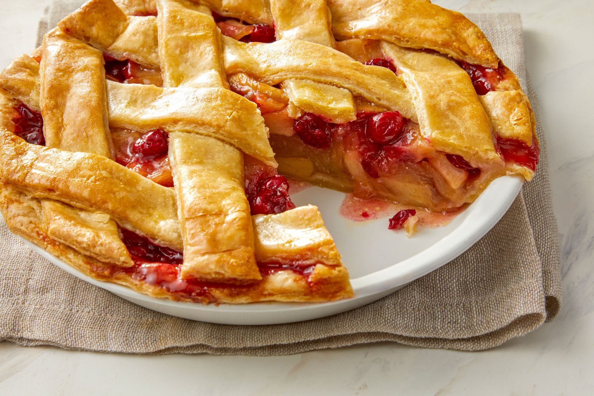 Close Shot of Cranberry Apple Pie Served on a Plate; Kitchen Napkin; Marble Background;