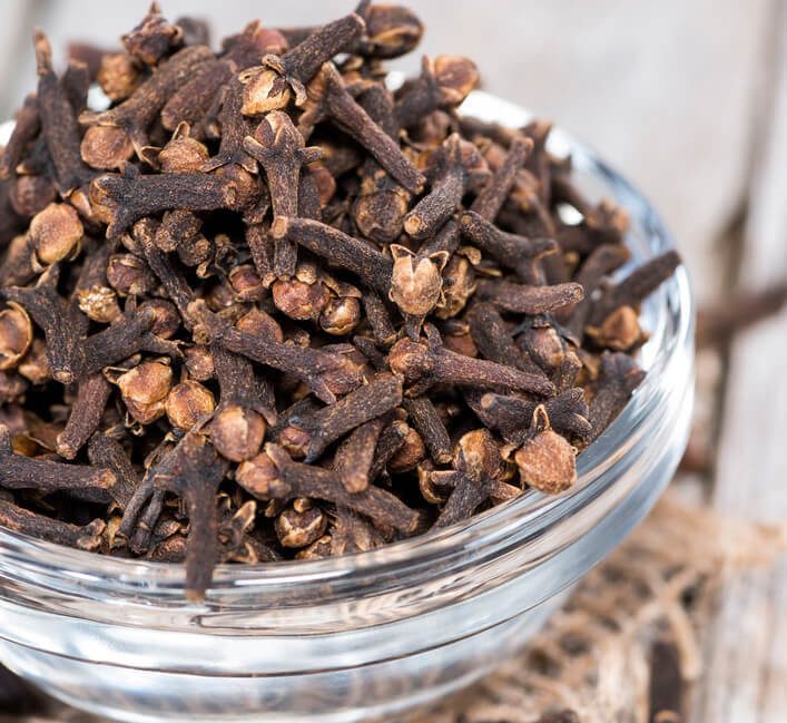 Small bowl with Cloves on vintage wooden background