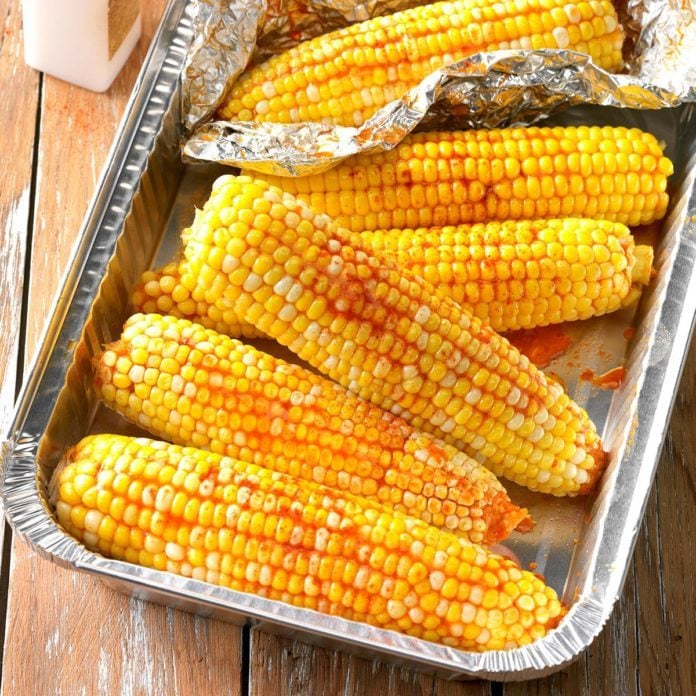 A foil pan loaded with ears of Slow-Cooker Sriracha Corn