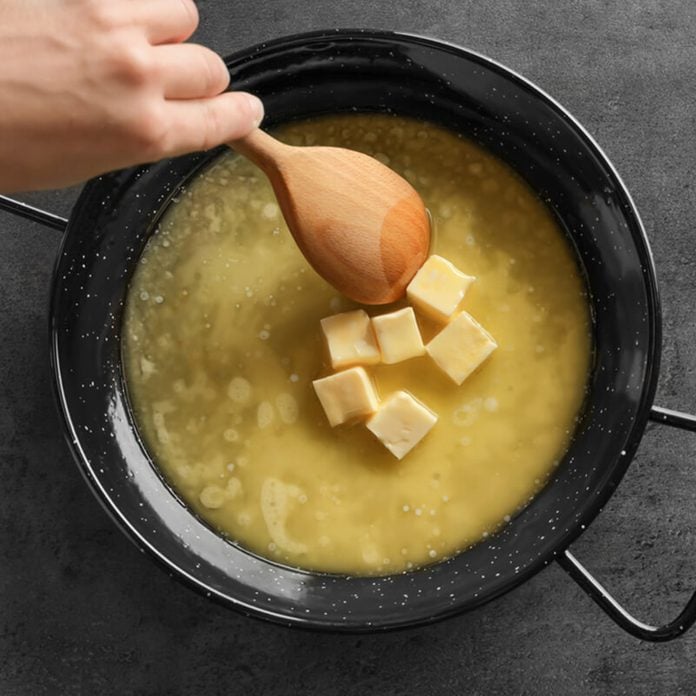 Woman stirring melting butter on frying pan, closeup