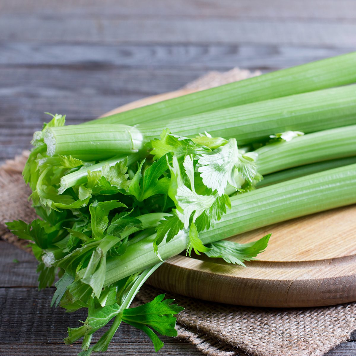 Fresh green celery stems on wooden cutting board