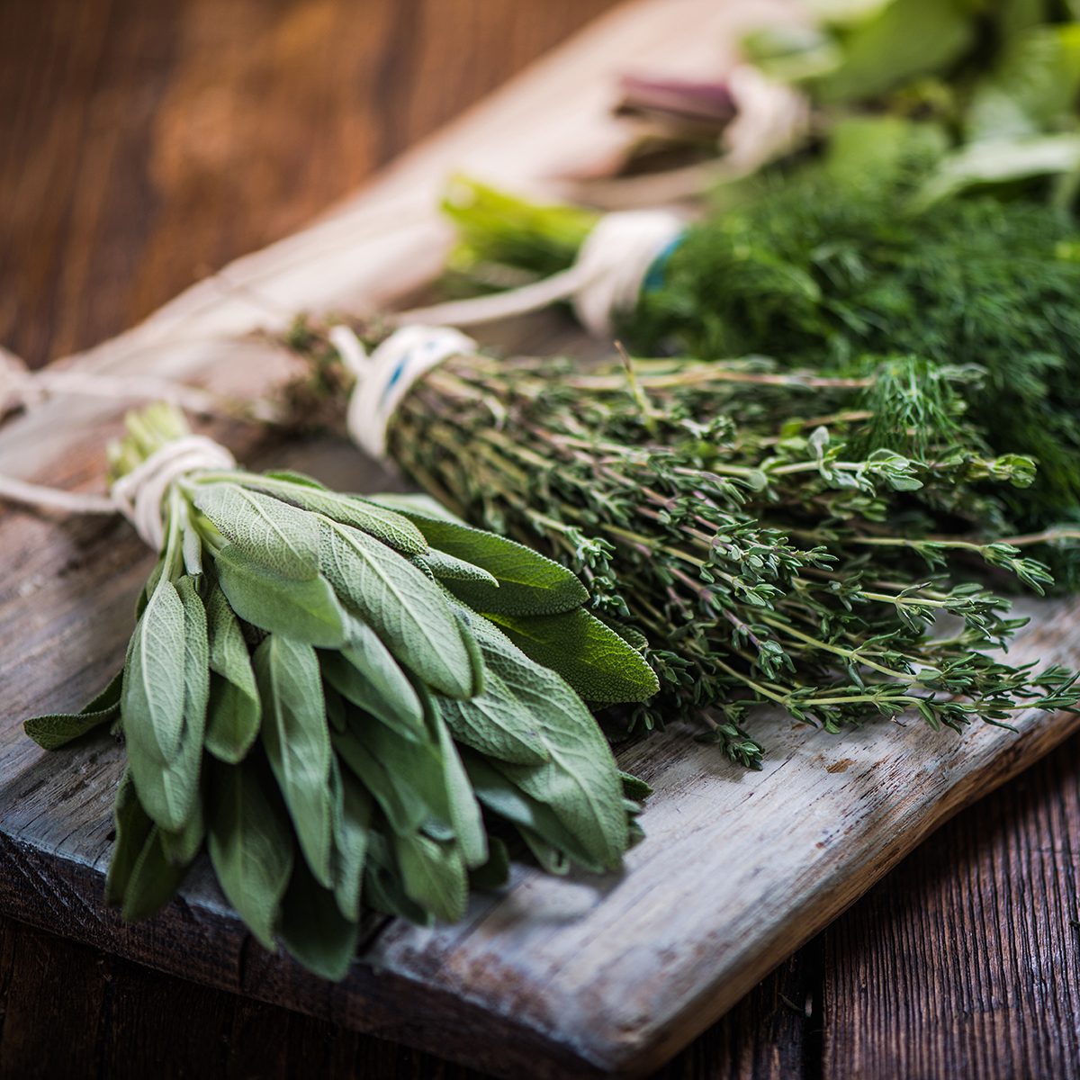 Basil,sage,dill,and thyme herbs on wooden board preparing for winter drying