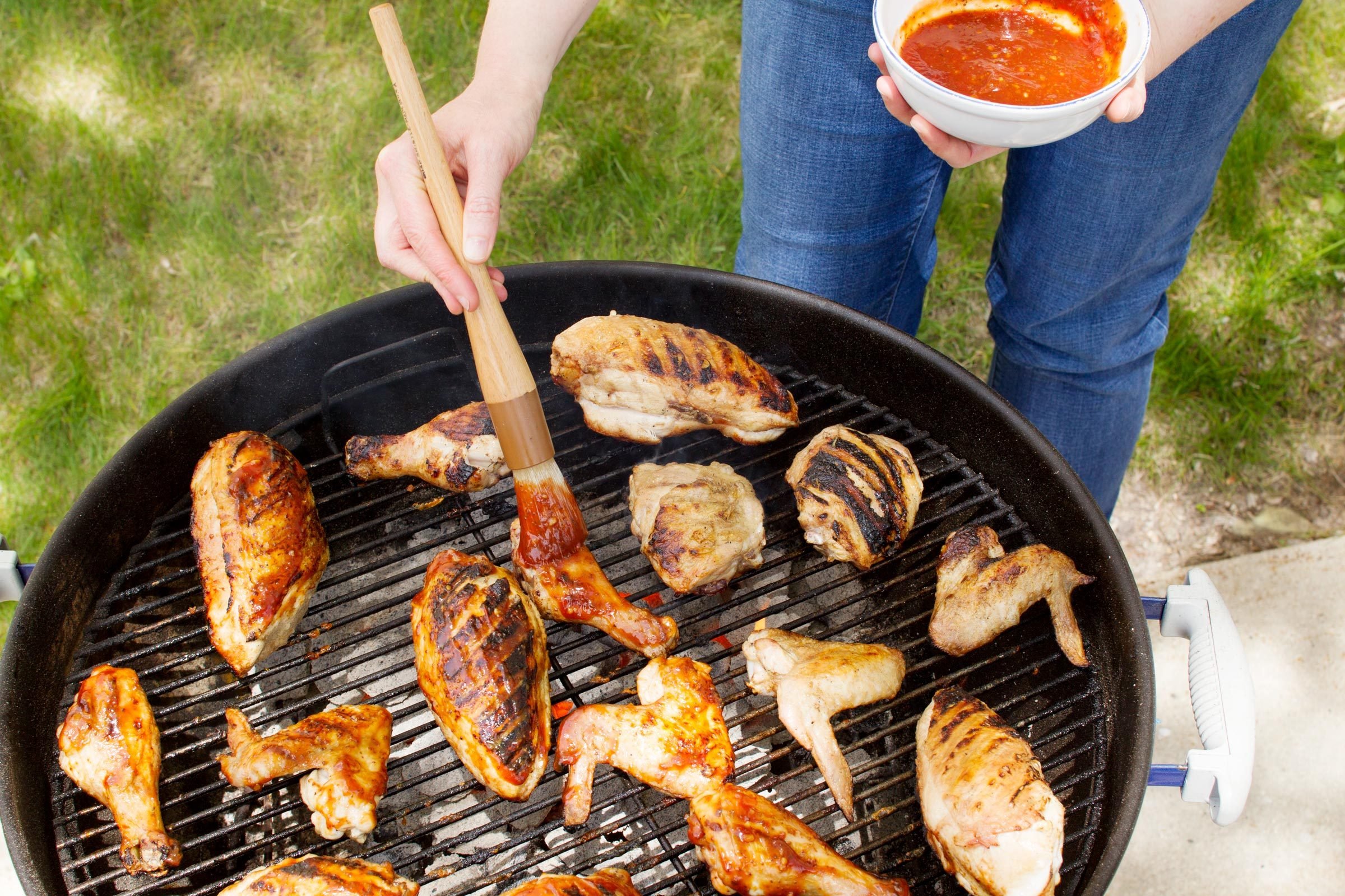 basting chicken wings on the grill with sauce