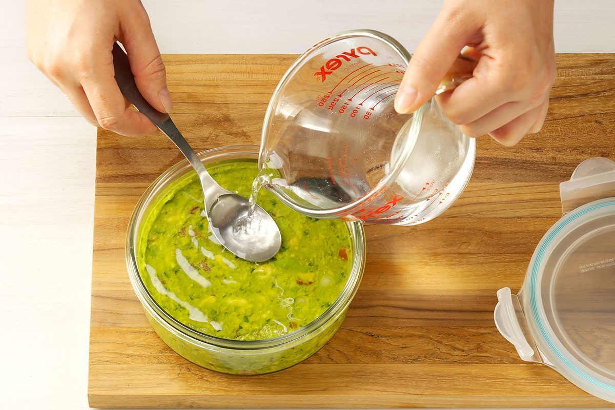 Submerging guacamole in water for peak freshness.