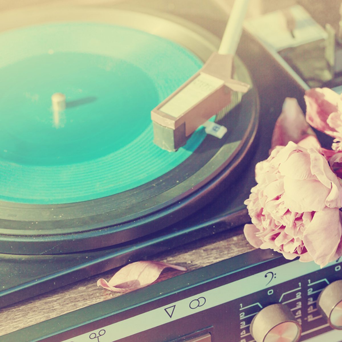 Old vintage good looking turntable playing a track with vinyl and flowers