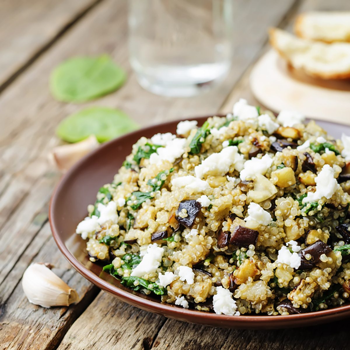 quinoa spinach eggplant feta salad on a dark wood background.