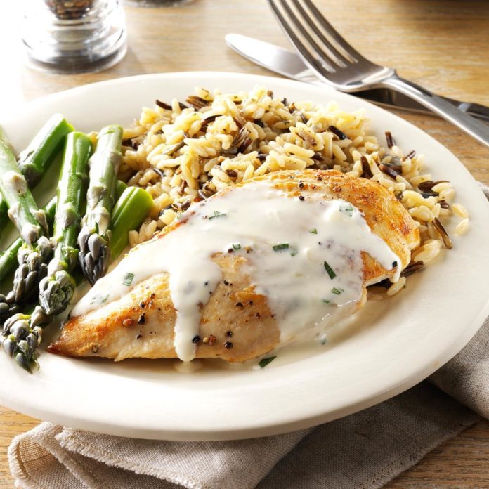 A plate with chicken in tarragon cream sauce, asparagus and rice.