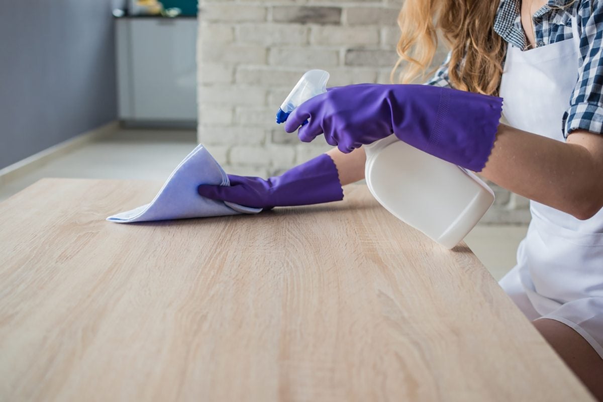 Female hands cleaning table in the living room.