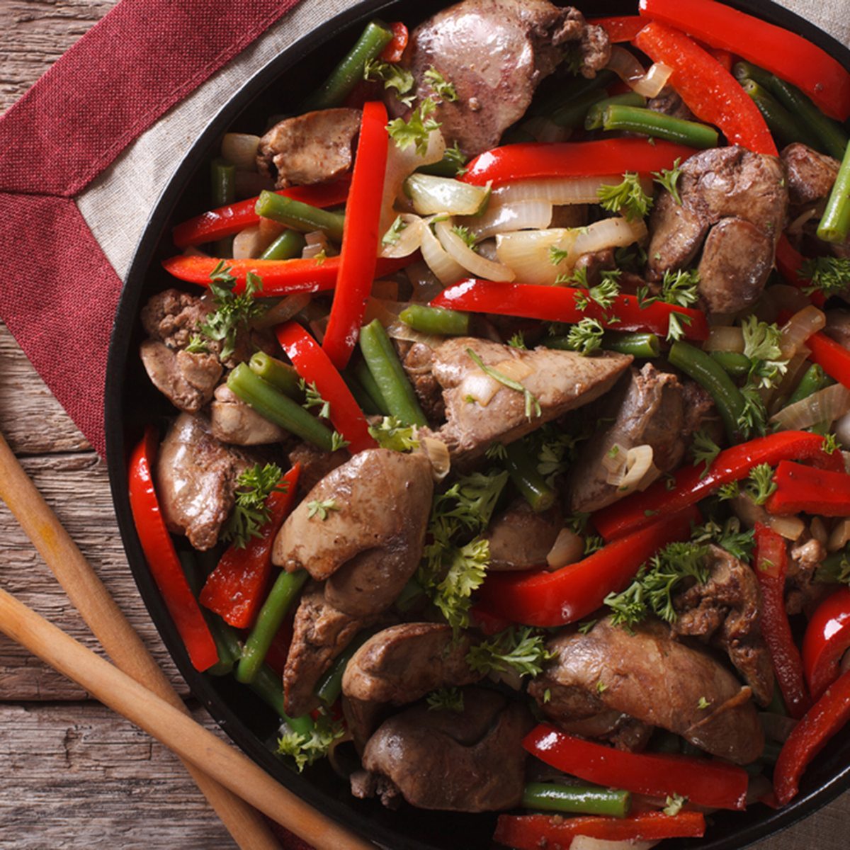 Chicken liver fried with vegetables close-up on a dish on the table.