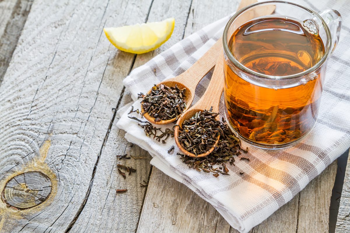 Black tea in glass cup, rustic wood background