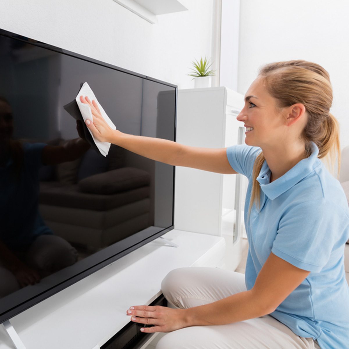 Young Smiling Woman Wiping Television Of Living Room At Home; Shutterstock ID 555958666; Job (TFH, TOH, RD, BNB, CWM, CM): Taste of Home