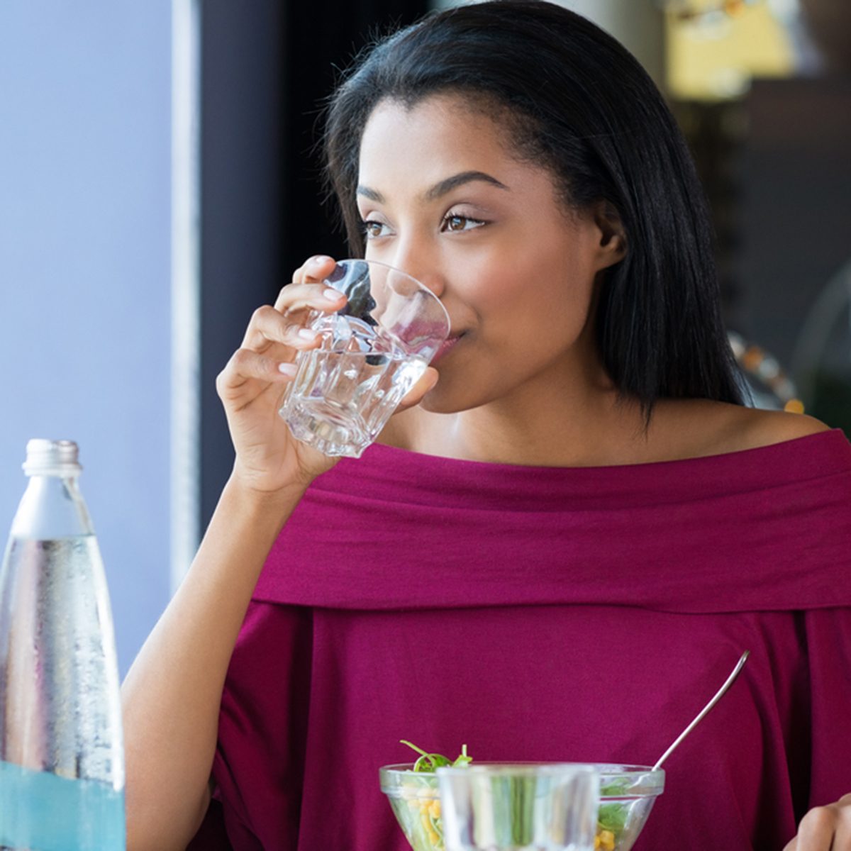 African girl drinking water during her lunch break at restaurant.