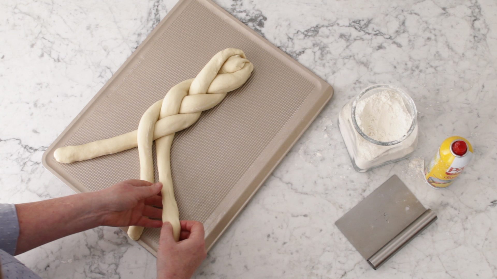 Person criss-crossing the strands of bread dough