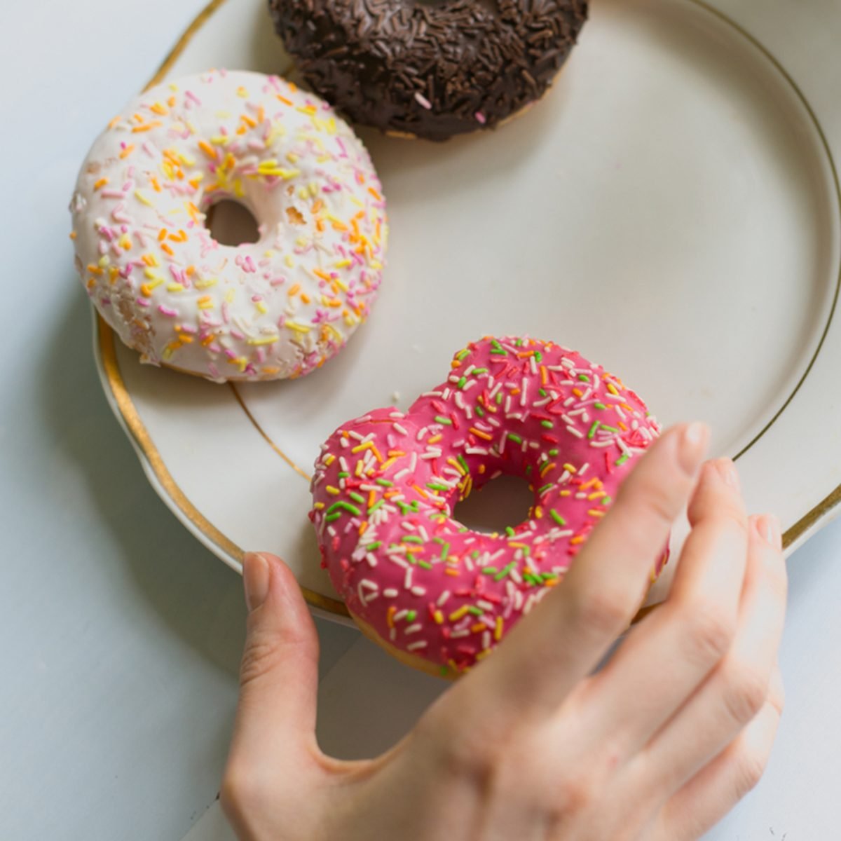 Donuts on a plate with a hand reaching towards them