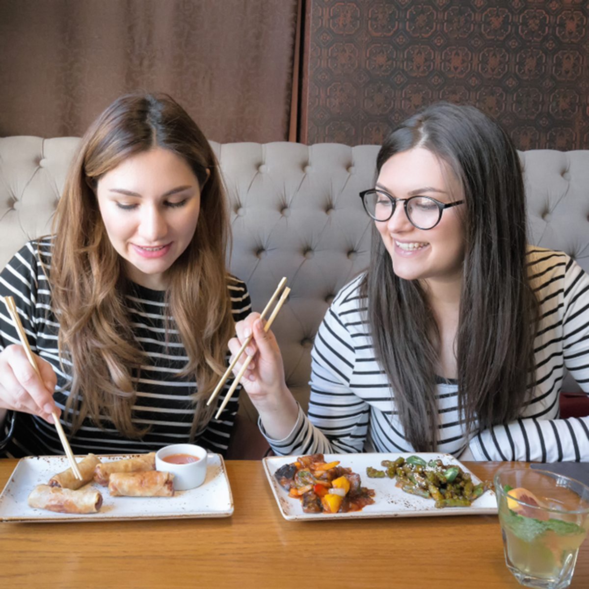 Lifestyle image of best friend girls ordering from menu in restaurant and deciding what to eat.