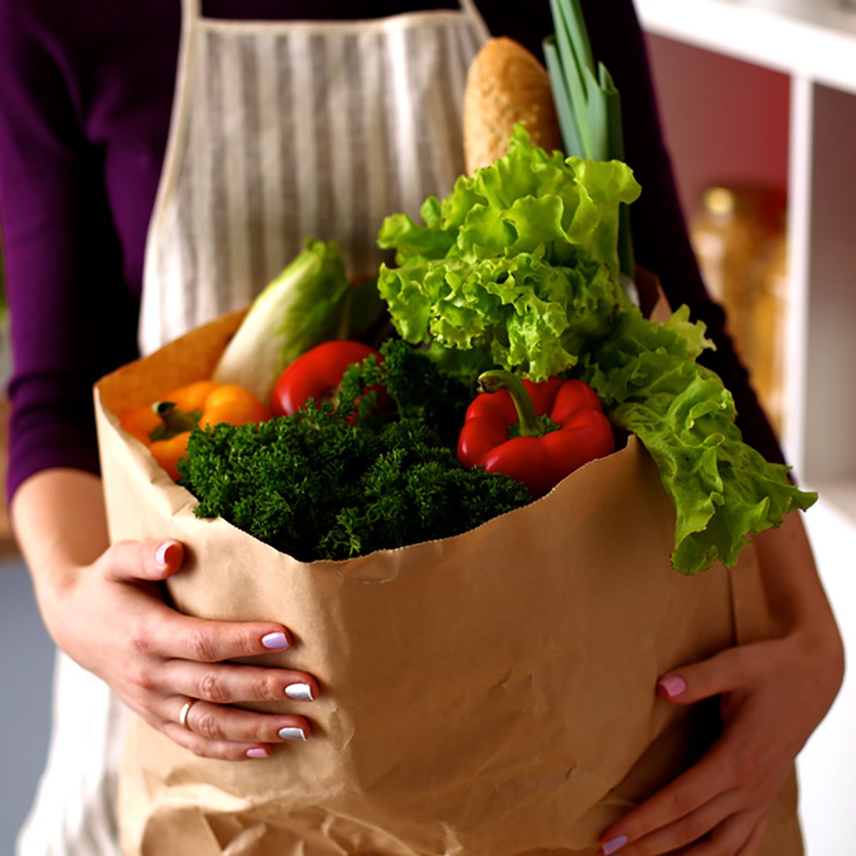 Young woman holding grocery shopping bag with vegetables