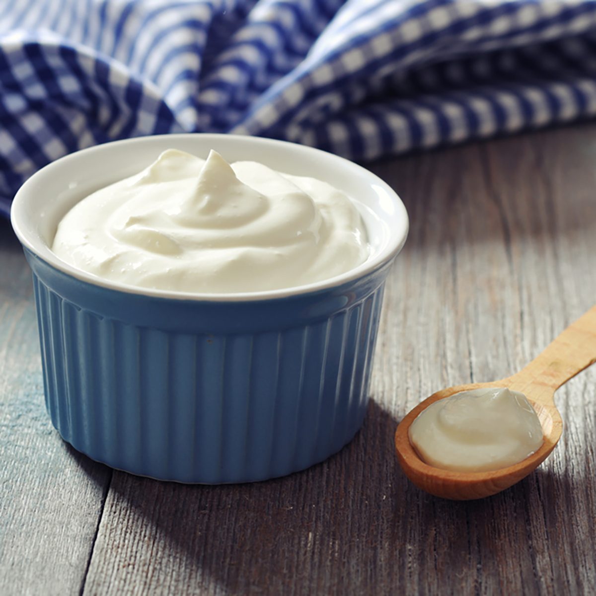 Greek yogurt in a ceramic bowl with spoons on wooden background