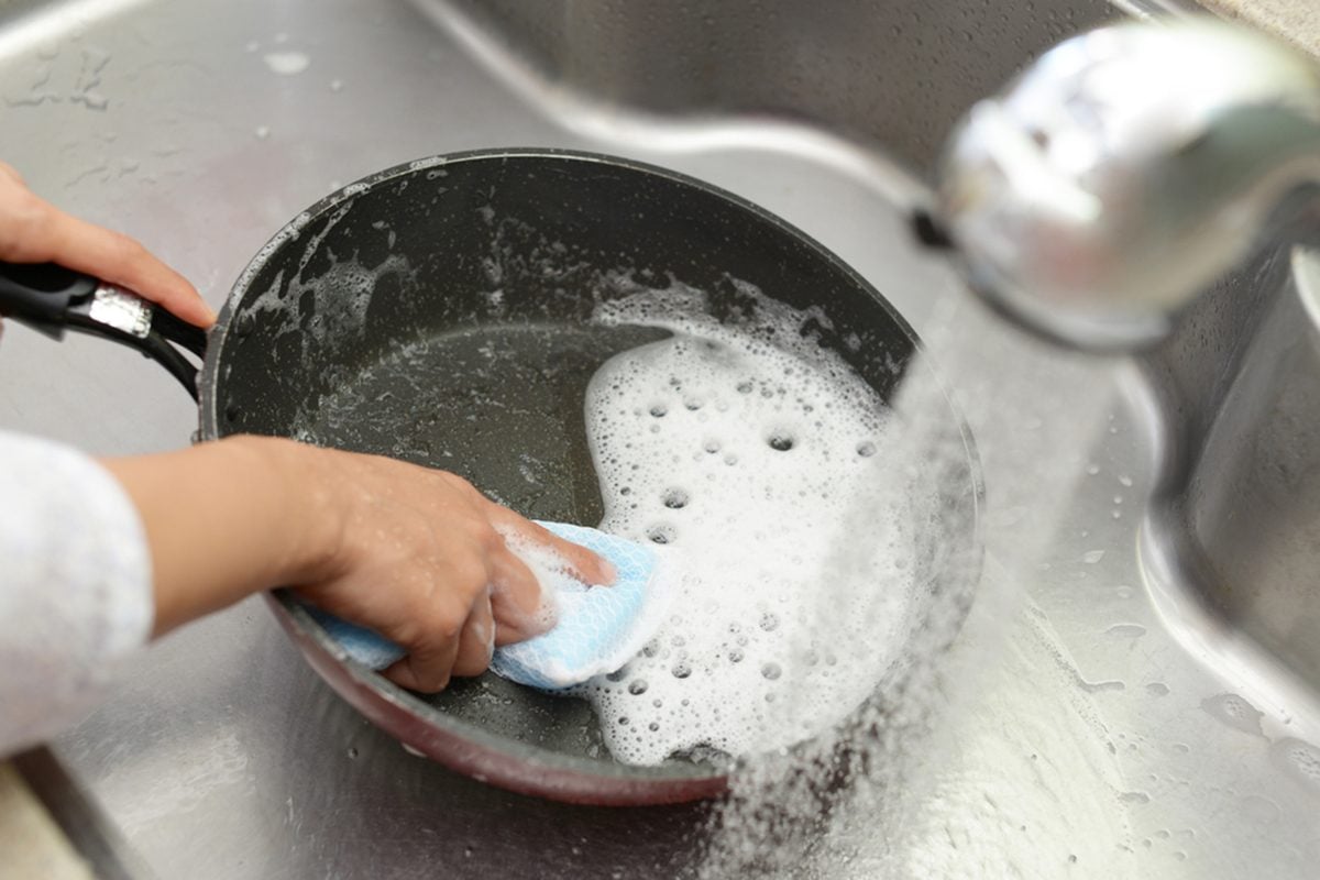 Hand cleaning the non stick pan with handy dish washing sponge