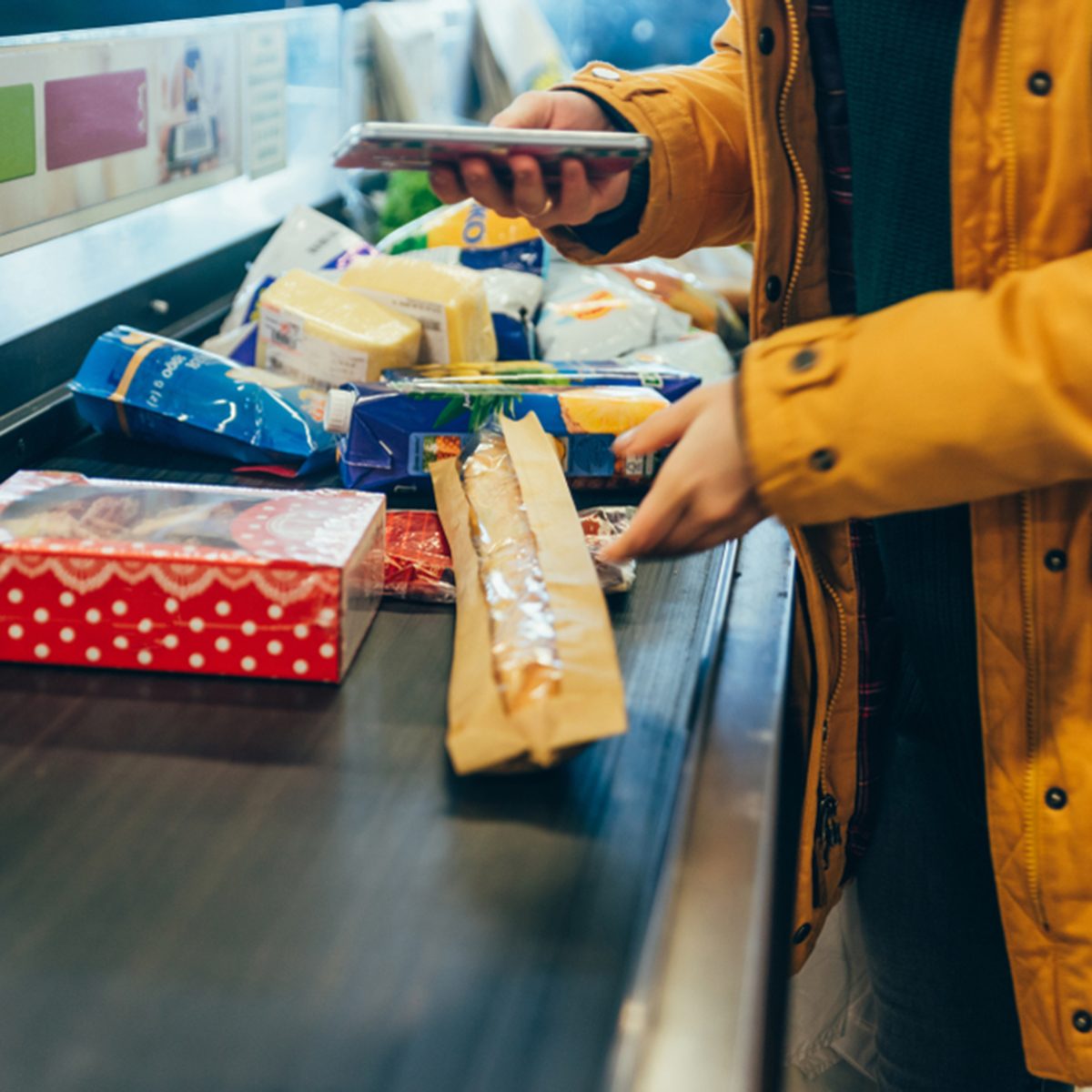 woman put products on cash line in store. grocery shopping.