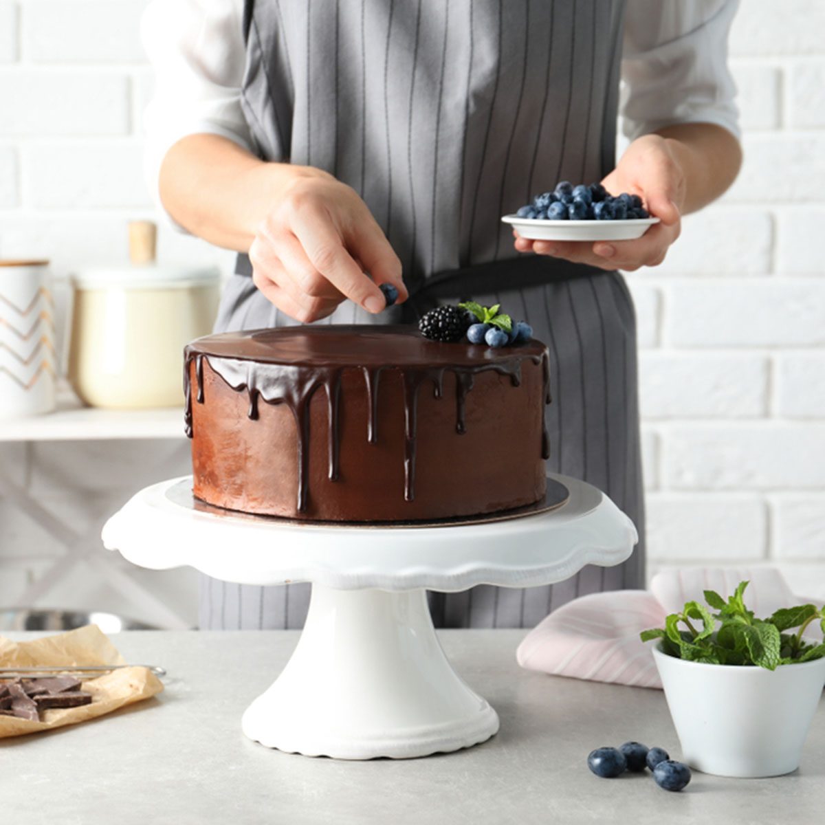 Baker decorating fresh delicious homemade chocolate cake with berries on table, closeup; Shutterstock ID 1167742222; Job (TFH, TOH, RD, BNB, CWM, CM): Taste of Home