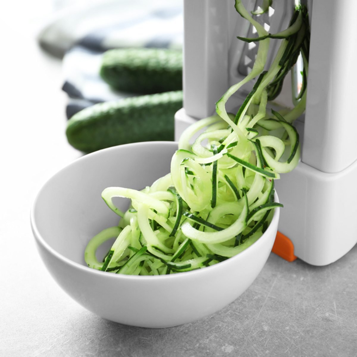 Spiral vegetable slicer with cucumber spaghetti on table