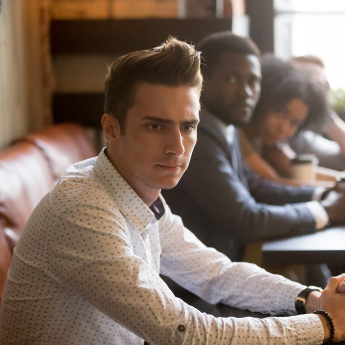 Diverse people looking at thoughtful frustrated man in cafe