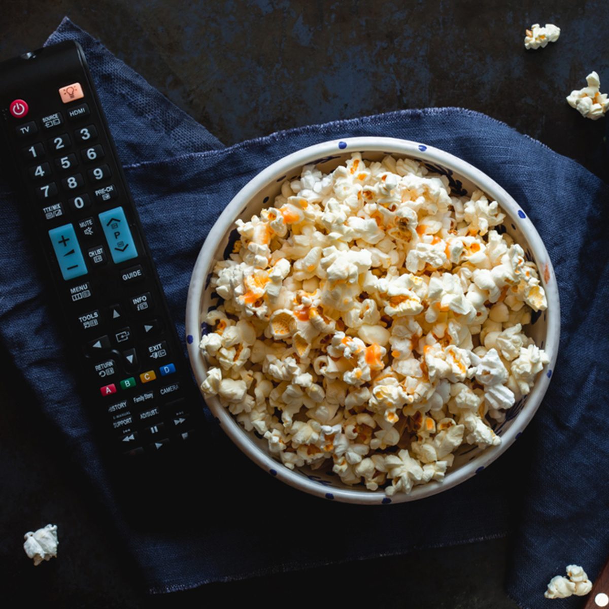 Bowl of popcorn with salted caramel, remote control TV, glass with milk on a blue tablecloth. View from above. Leisure. Watch TV.; Shutterstock ID 659564446; Job (TFH, TOH, RD, BNB, CWM, CM): TOH