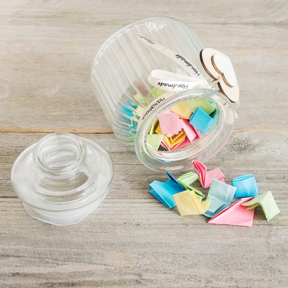 Glass jar with handmade wooden hearts decorations and ribbon filled with colorful pastel paper notes spilling over.; Shutterstock ID 696530689; Job (TFH, TOH, RD, BNB, CWM, CM): TOH