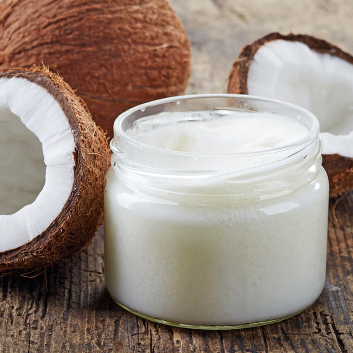 coconut oil and fresh coconuts on old wooden table