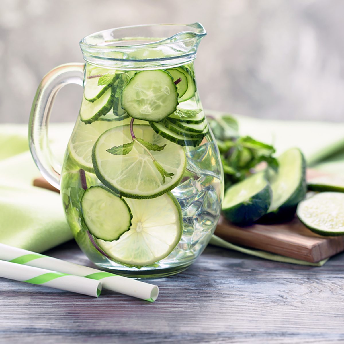 Infused water with cucumber, lime and mint on grey rustic background