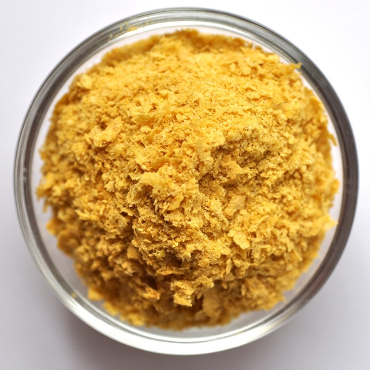 Nutritional yeast in a bowl close-up on white background