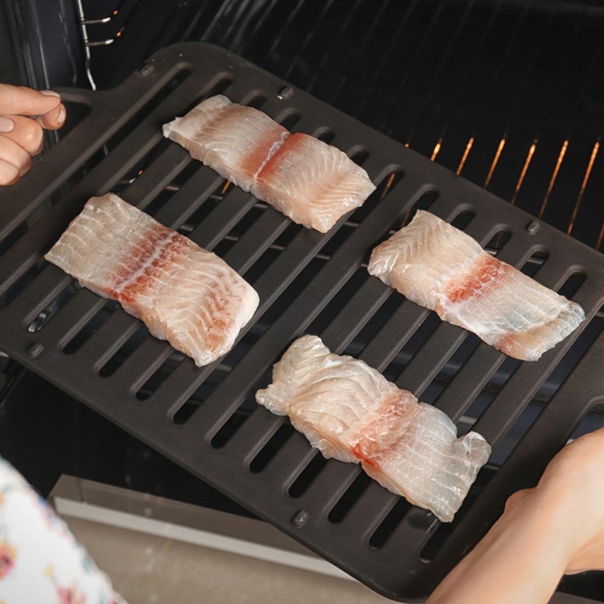 Woman putting broiler pan with fish fillet slices into oven; Shutterstock ID 715921033; Job (TFH, TOH, RD, BNB, CWM, CM): TOH