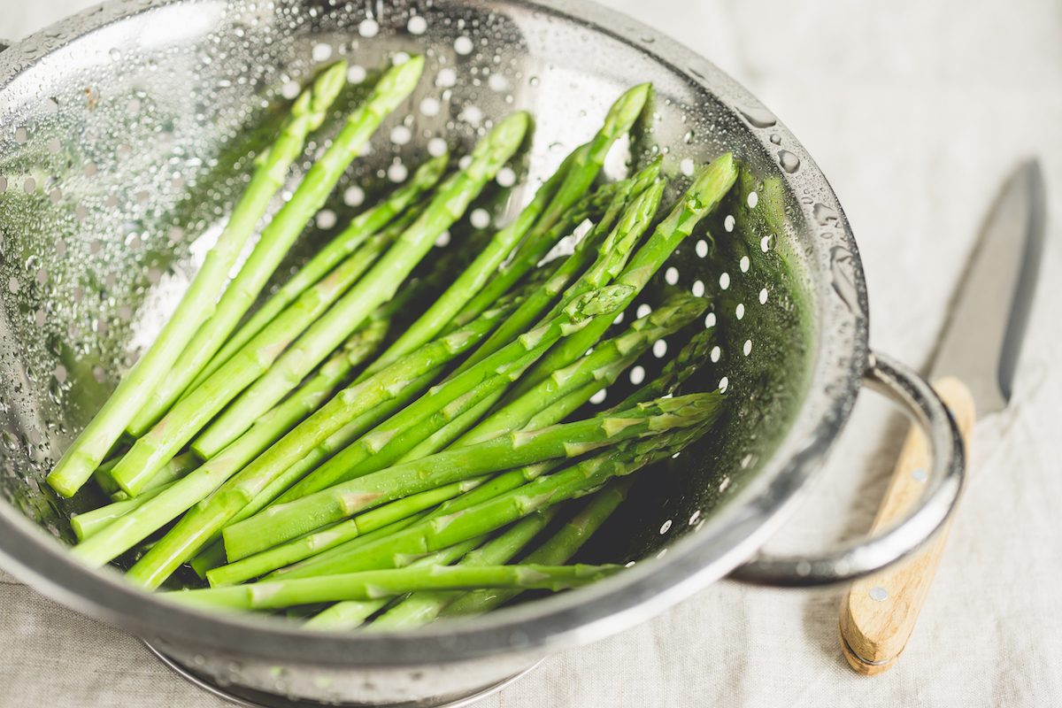 Washed asparagus in a metal collander.