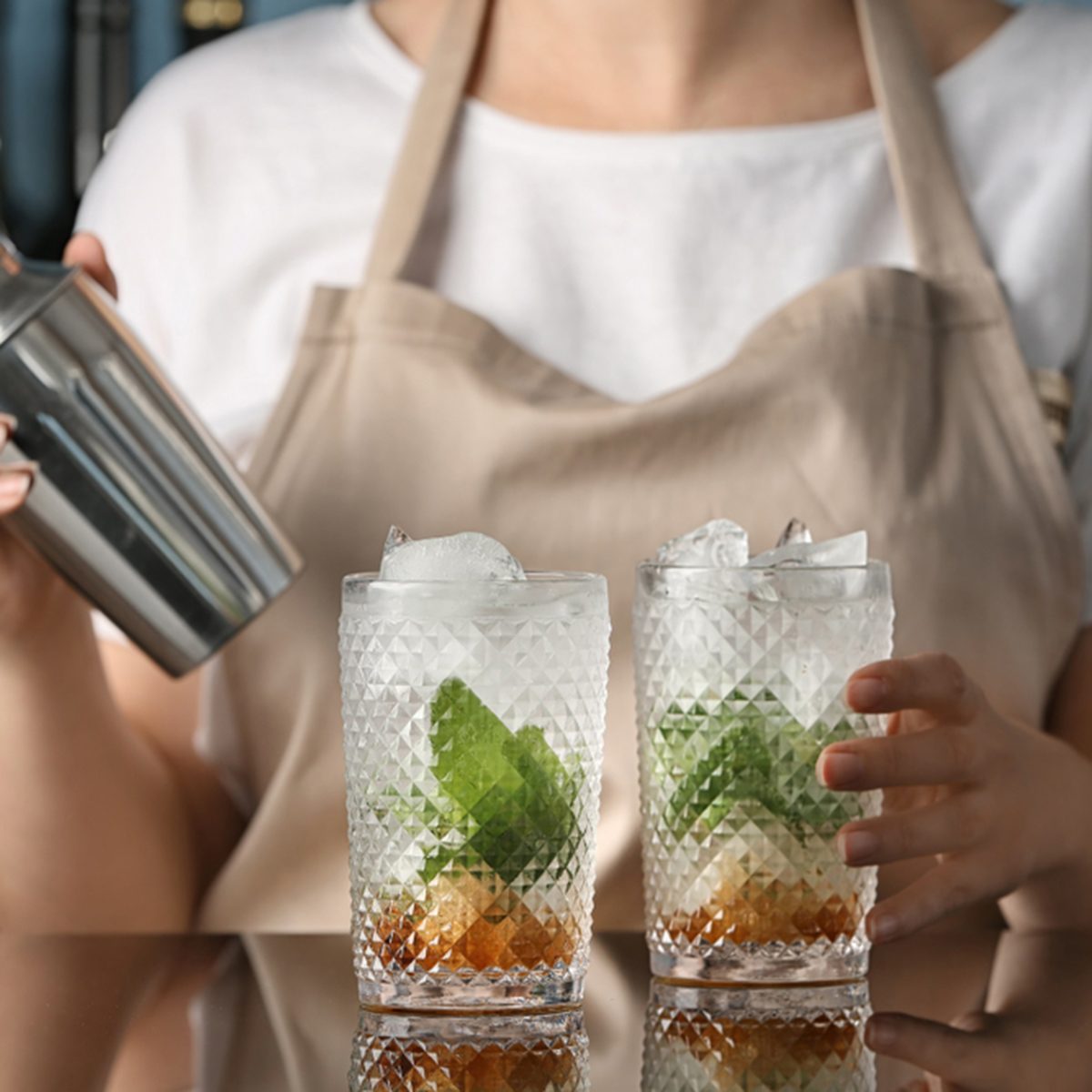 Bartender preparing delicious mint julep cocktail at table