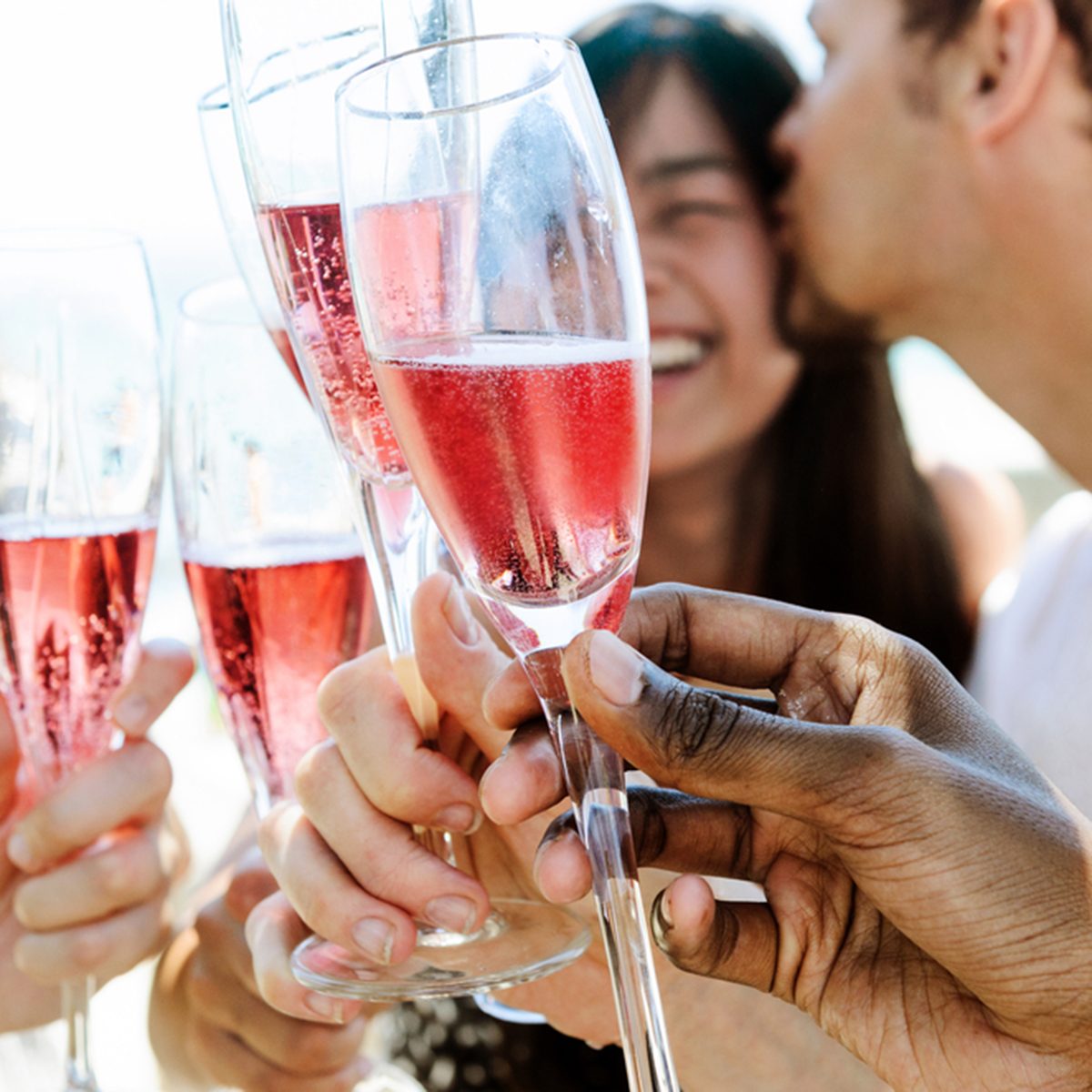 Beautiful mix race couple celebrating their engagement with champagne and their friends on the beach