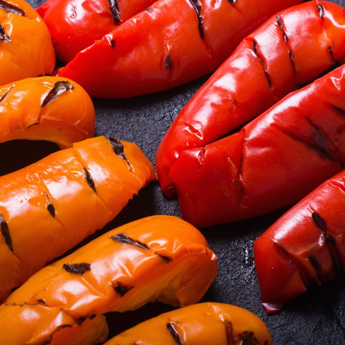 Orange and red grilled peppers on black stone