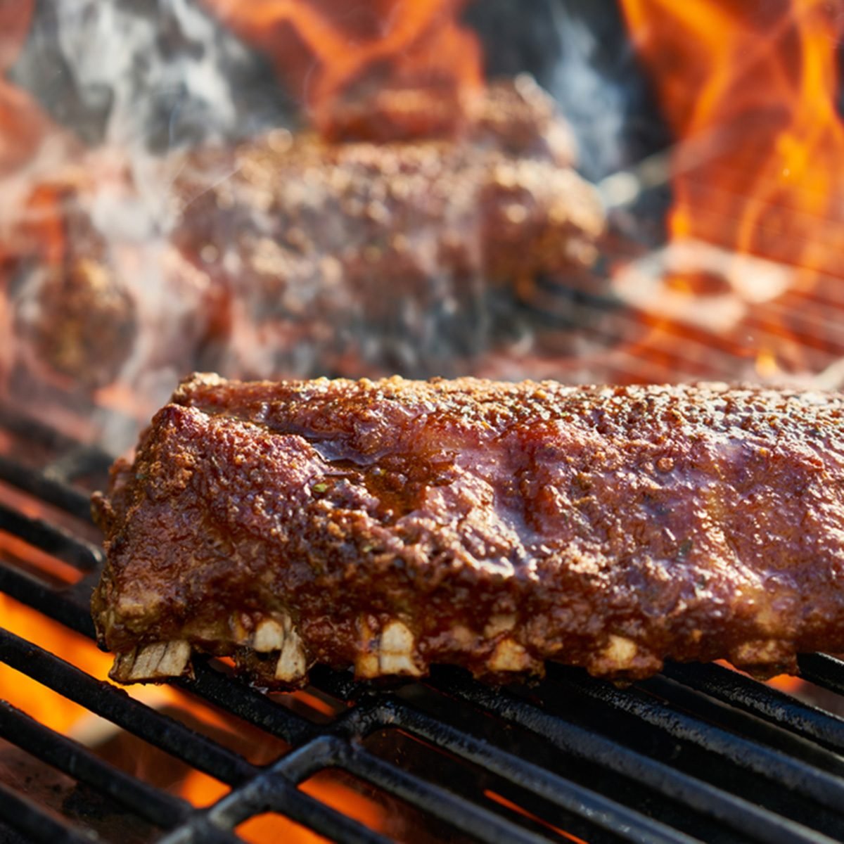 grilling baby back pork ribs over flaming grill