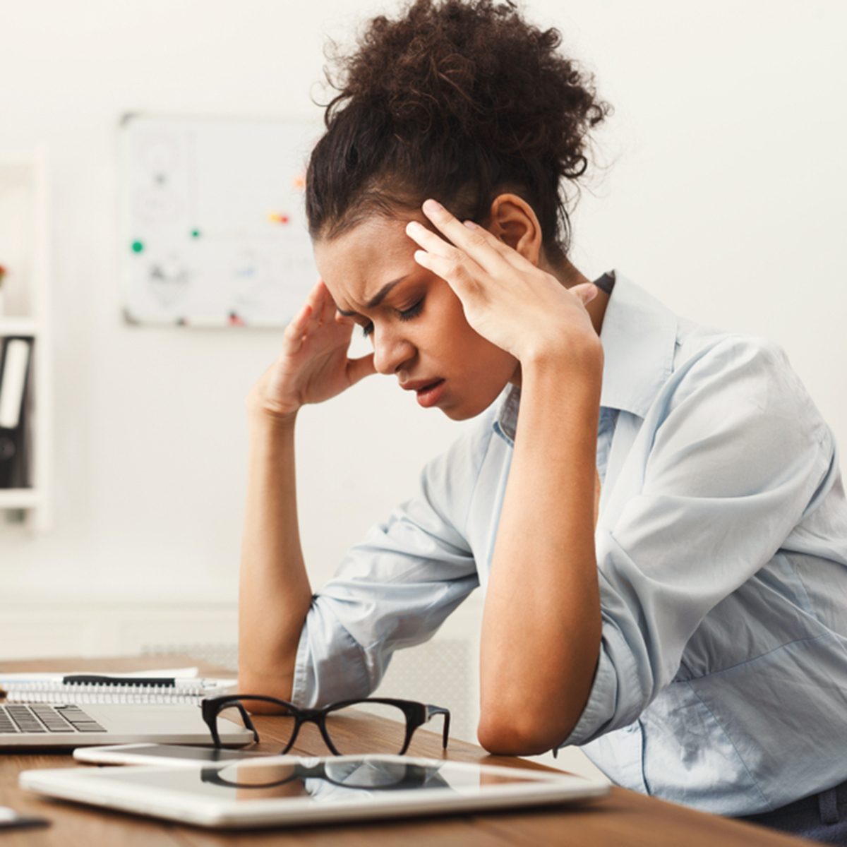 Tired african-american business woman with headache at office