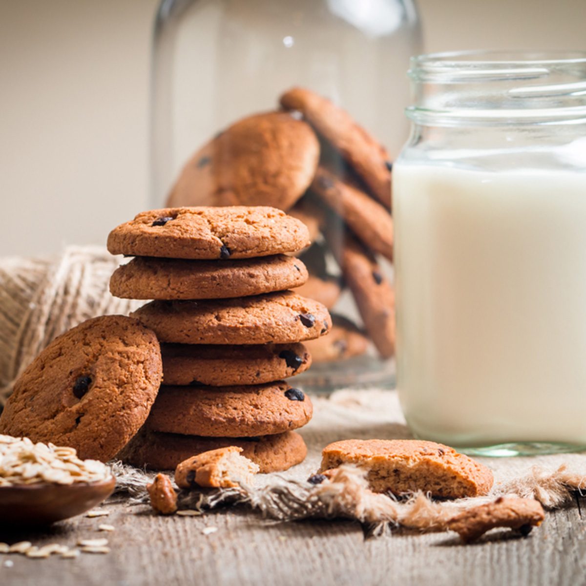 Chocolate chip cookies with milk on burlap and rustic wooden table