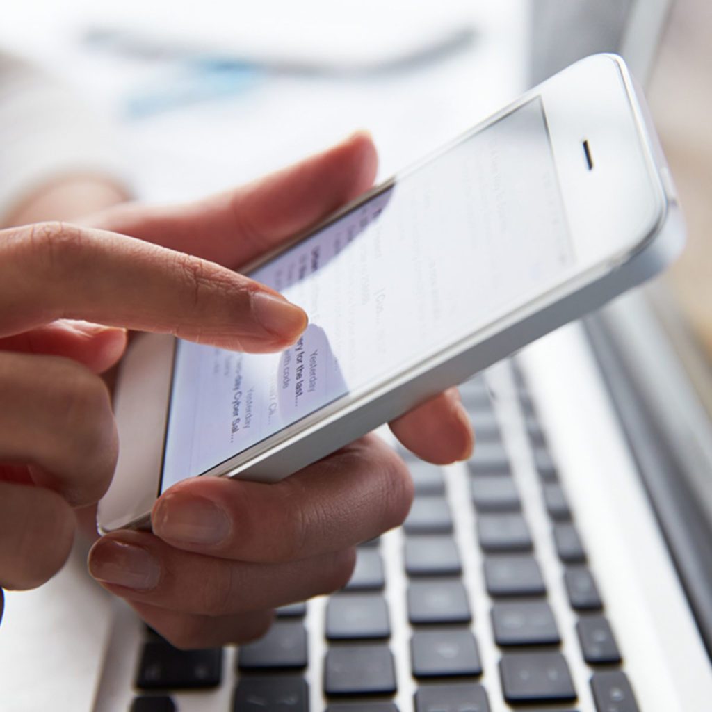 Close Up Of Person At Laptop Using Mobile Phone; Shutterstock ID 243438799